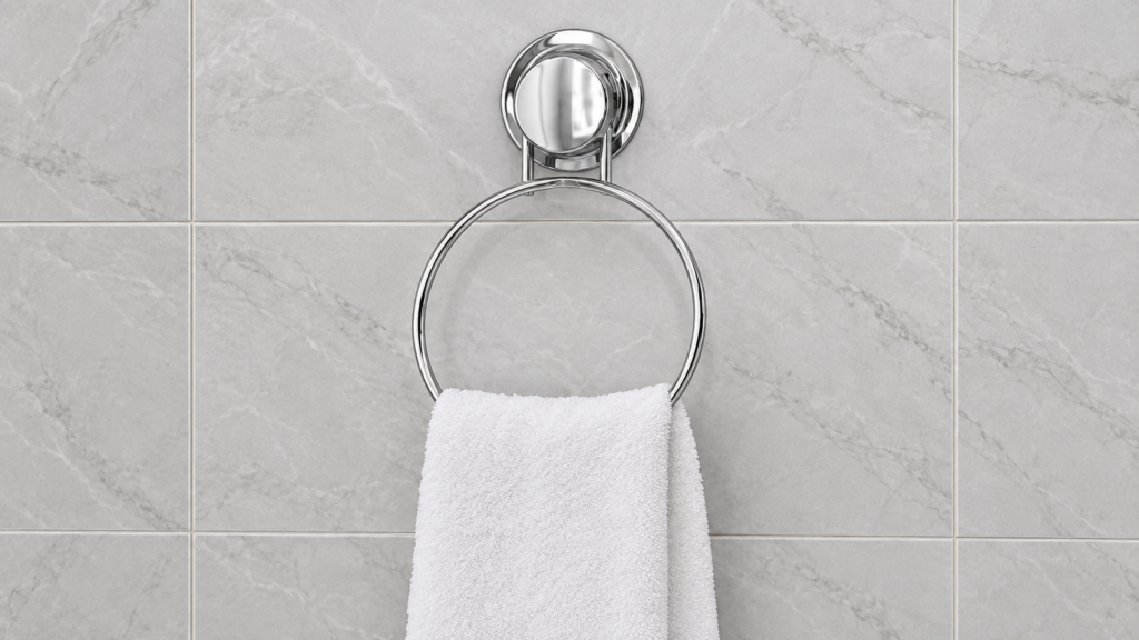 Chrome suction cup towel ring holding a hand towel on smooth bathroom tile.