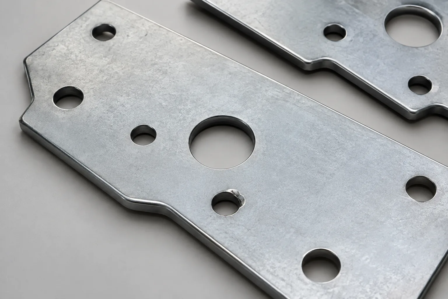 clean punched metal mounting plates with a small loose slug and one subtle double-hit witness mark, no dramatic damage.