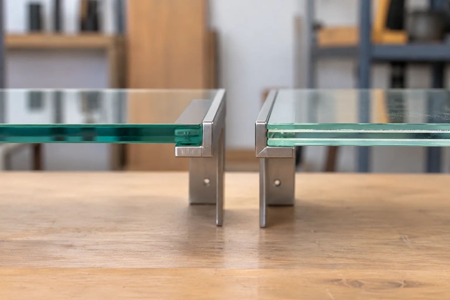 Two glass shelf samples in metal supports, one tempered and one laminated, visually distinct edge construction
