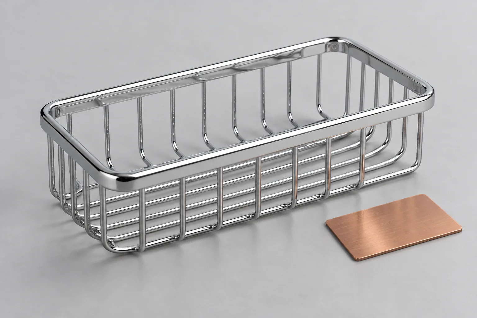 Polished chrome wire bathroom basket beside an unlabelled copper-tone plating sample coupon