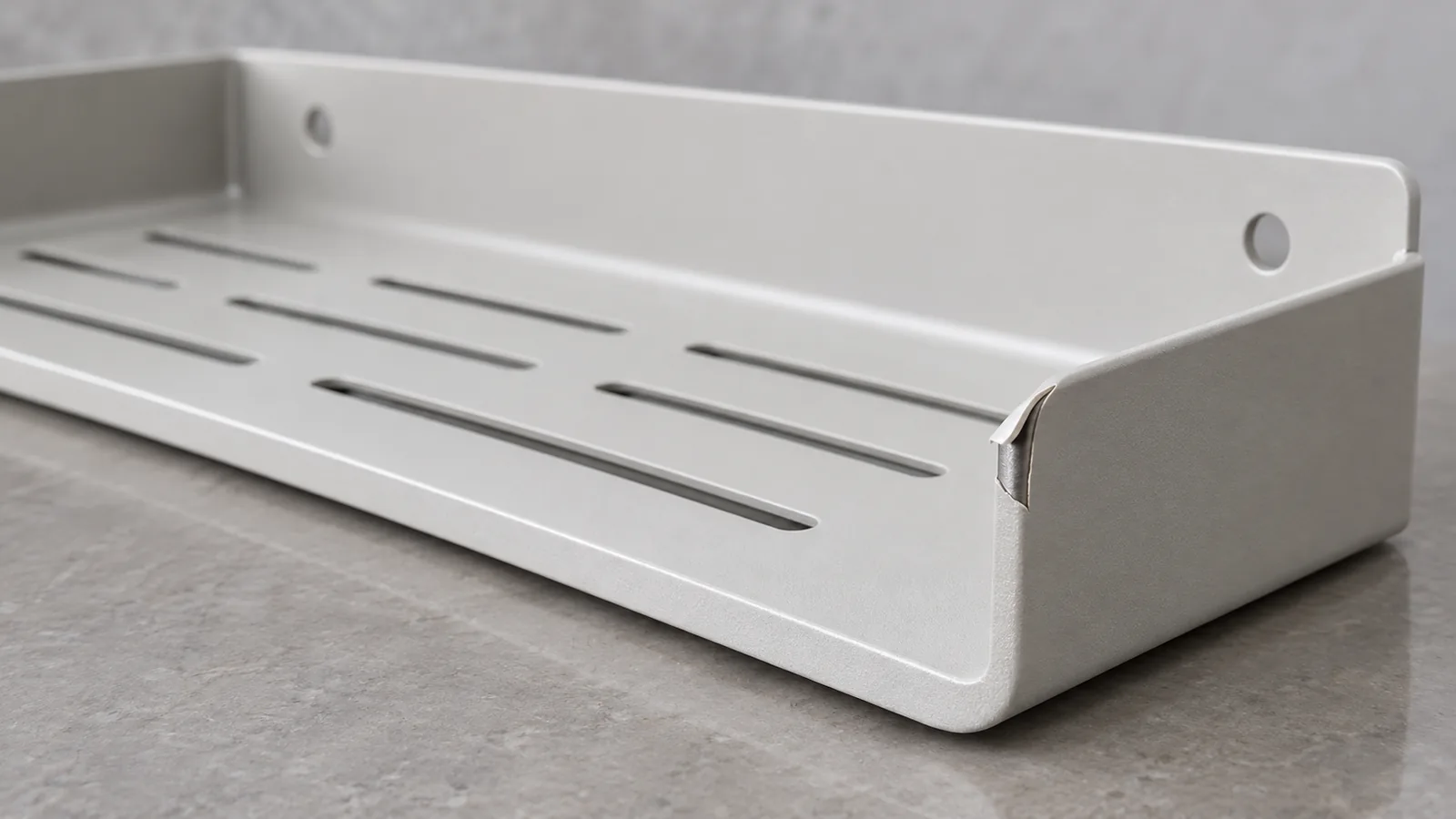 Generic powder-coated bathroom shelf sample with a small localized lifted coating edge; root cause unconfirmed.